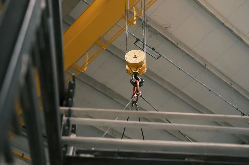 Yellow overhead crane hook suspended in an industrial warehouse